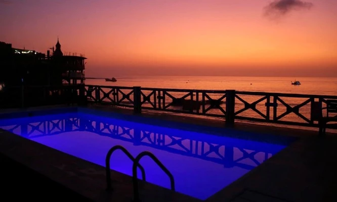 Hospedaje para 02:  Piscina frente al mar, área de juegos, habitación matrimonial